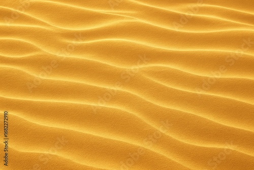 Golden sand texture with gentle wavy dune patterns under sunlight. Desert background perfect for travel, nature, and texture design themes.