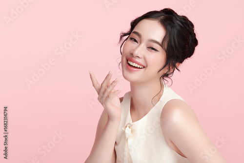 A beautiful young Asian woman with clean, fresh skin against a pink background. Skincare, facial treatment, cosmetology, beauty, and spa. An elegant portrait of an Asian woman.