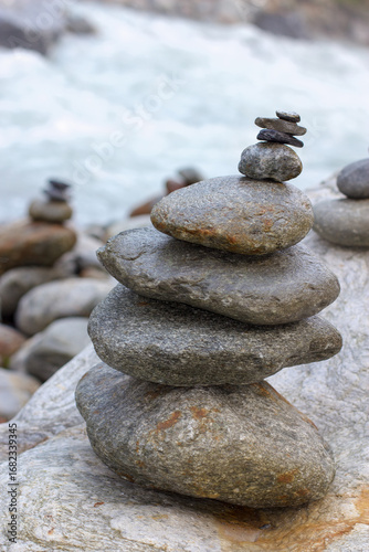 Canvas Print Stacked stones alongside a stream in the Swiss Alps