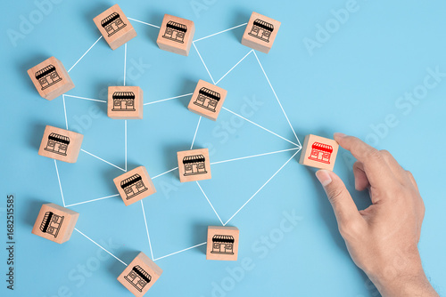 Distribution franchise branch store. Hand placing red franchising shop cube wooden block business partner alliance network icon symbol. Market growth expansion financial loan marketing