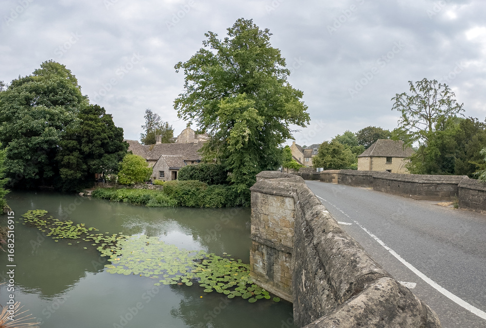 Fototapeta premium Tranquil Village Bridge Over Reflective River Scene