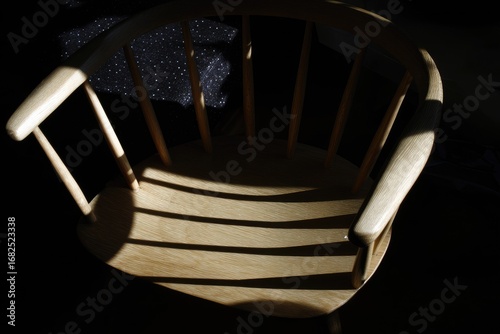 Light-streaked wooden armchair, dark background