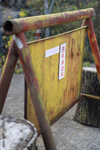 Korean signs are posted on rusty yellow metal plates: 