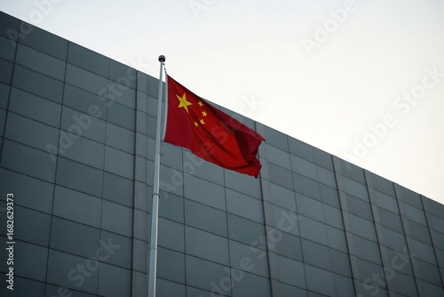 Minimalist architectural photograph of the Chinese flag hanging still against the clean, geometric lines of a modern building.