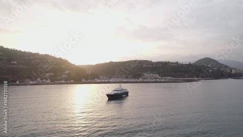 Drone footage captures tranquil marina at Mandelieu La Napoule, South of France, during sunset. This scene features yachts, charming villages, lush hills, highlighting Mediterranean coast