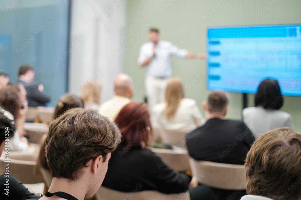 Fototapeta premium Group of people attending a presentation where speaker explains concepts using visual aids