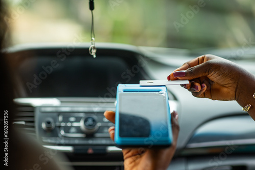 Konstfotografi African woman making contactless credit card payment for transport fare using POS terminal inside a car