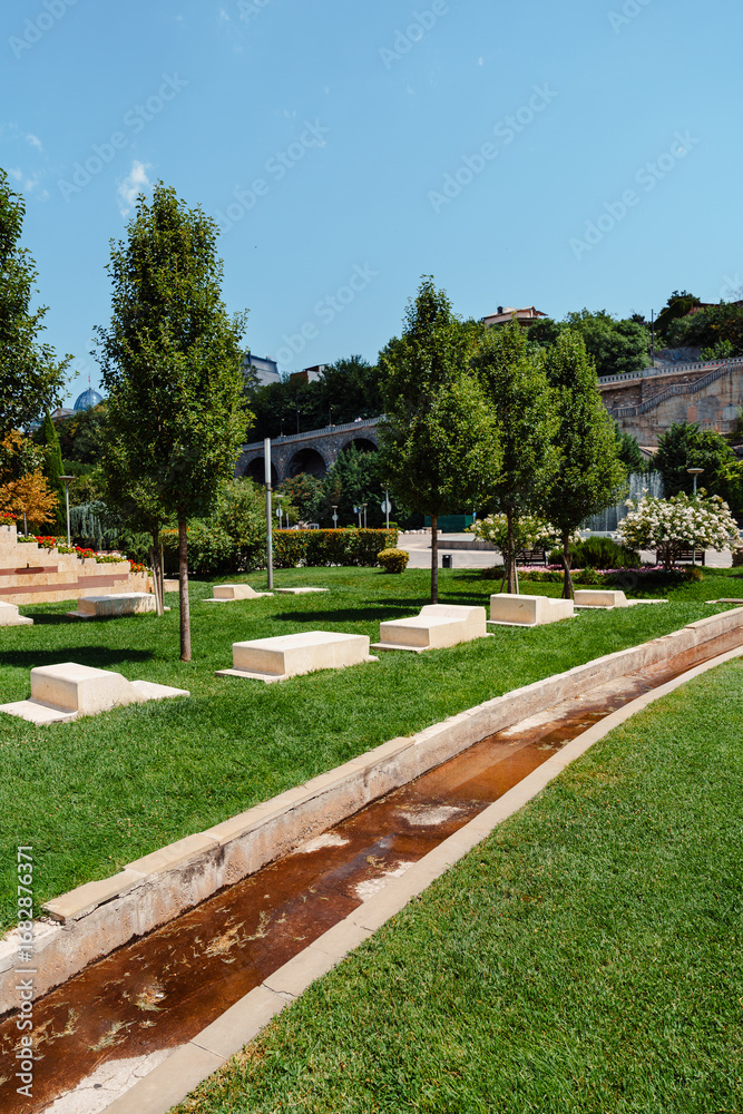 Obraz premium Tranquil landscape with manicured greenery and a gentle water feature in a serene park setting