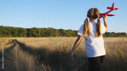 Wallpaper Mural Carefree child plays with toy plane jogging through country trail. Happy small girl running with airplane along path near grass field. Cute kid having fun at nature and enjoying freedom. Rear view Torontodigital.ca