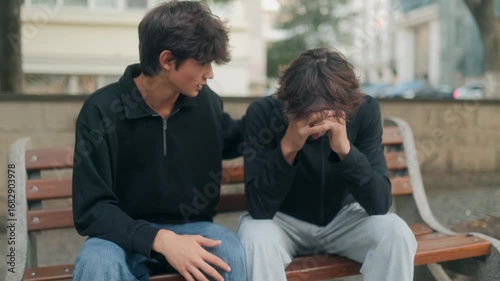 Teen comforting his sad friend outdoors, showing empathy and emotional support