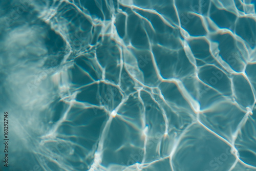 Swimming pool with clear blue water with sunlight shadow reflections. Minimalistic aesthetic summer vacation concept background	