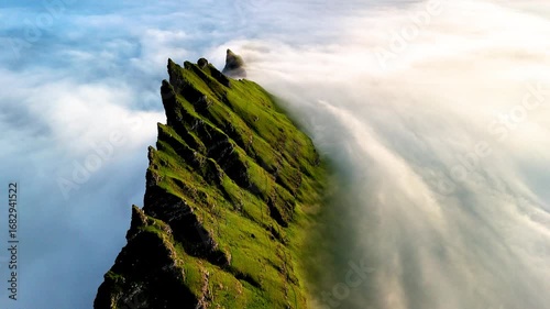 Explore the dramatic landscape of Drangarnir cliff in the Faroe Islands, where rugged peaks rise above a sea of soft clouds, creating a breathtaking natural spectacle at dawn.