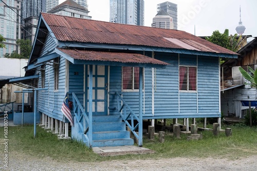 Canvas Print A traditional blue house located in Kampung Baru, with modern buildings in the background