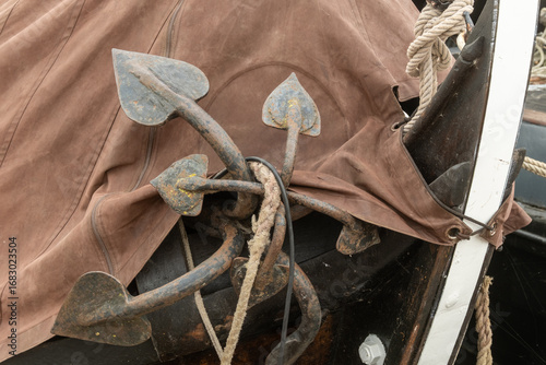 Wall Mural Rusty grapnel anchors hanging on side of wooden boat
