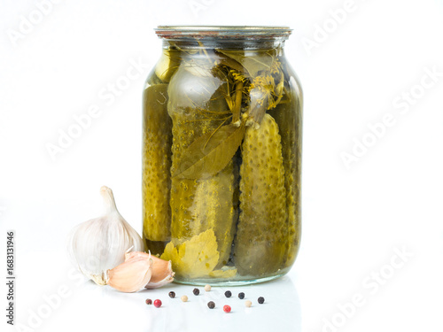 Pickled cucumbers isolated. Pickles in glass jar with garlic and peppercorn isolated on white background. Salted cucumber in jar isolated