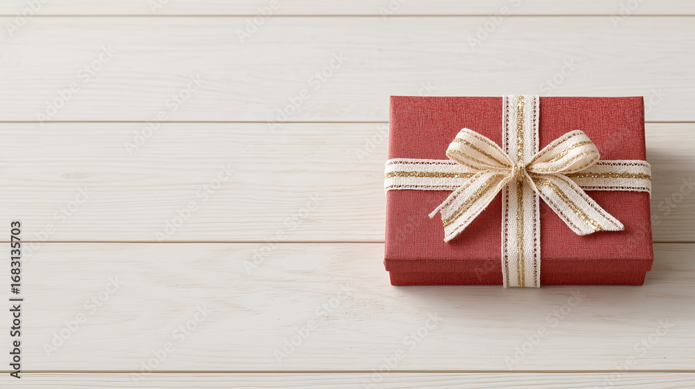 Fototapeta premium red gift box wrapped in a striped bow on top of a wood table