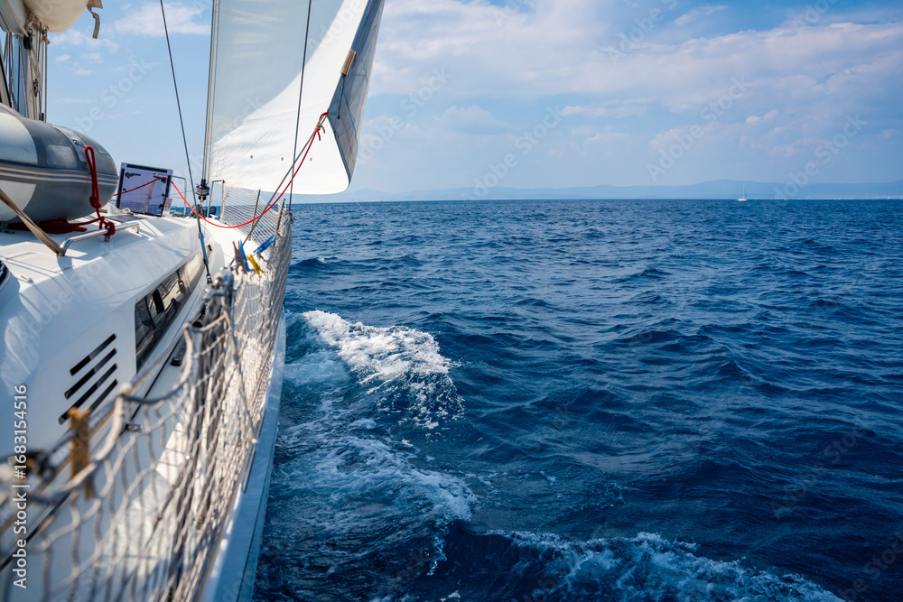 Fototapeta premium Side of a sailing yacht cutting through the sea with full sails near Croatia. Motion, freedom, sailing lifestyle and adventure on the open water.