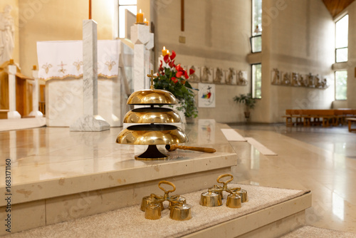 The interior of a modern church with a marble altar, church bells and religious sculptures along the wall. A calm spiritual atmosphere.