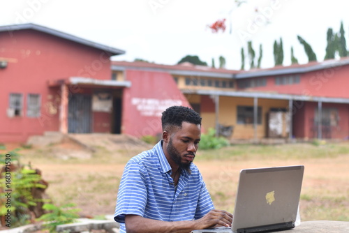 African American man works with his laptop sitting in a park