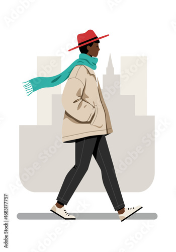 A person is walking in urban with a stylish look. The individual wears a red hat and a green scarf, carrying a modern jacket and dark pants