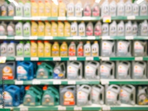 Blurred colorful motor oil bottles on shelves in supermarket as background