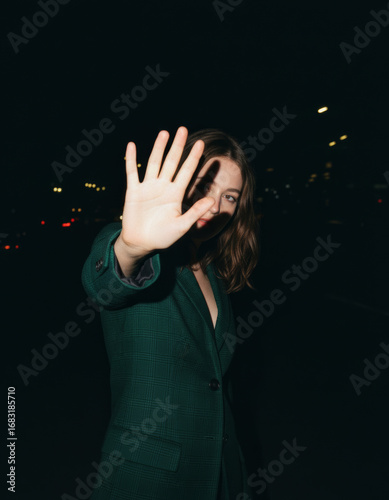 Woman Shielding Face from Camera in Dark Setting