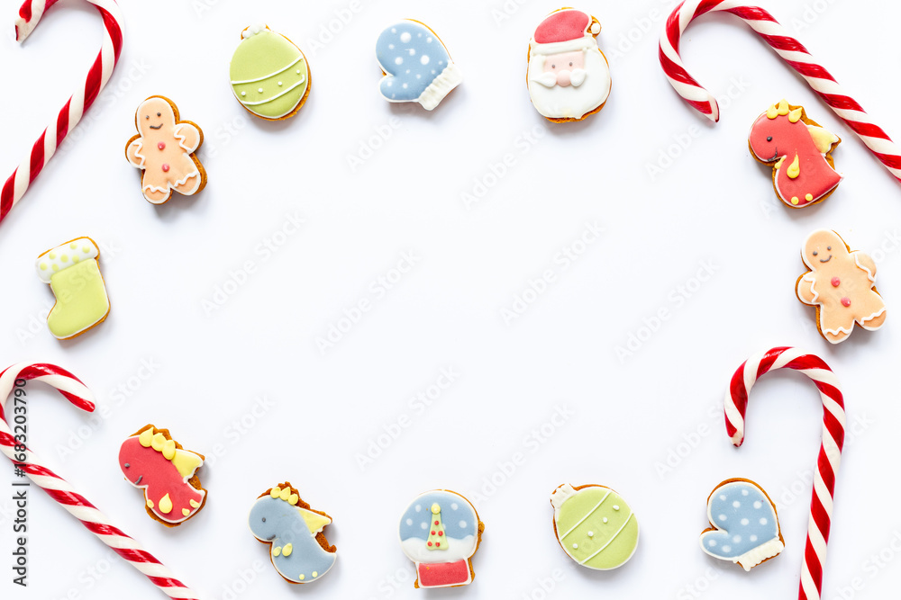 Fototapeta premium Festive composition of Christmas and New Year gingerbread cookies and Christmas Candy Canes on white background, top view. Greeting concept