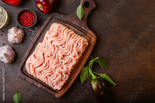 Raw minced meat on cutting board and ingredients. Ground meat with ingredients for cooking on dark background with copy space. Top view