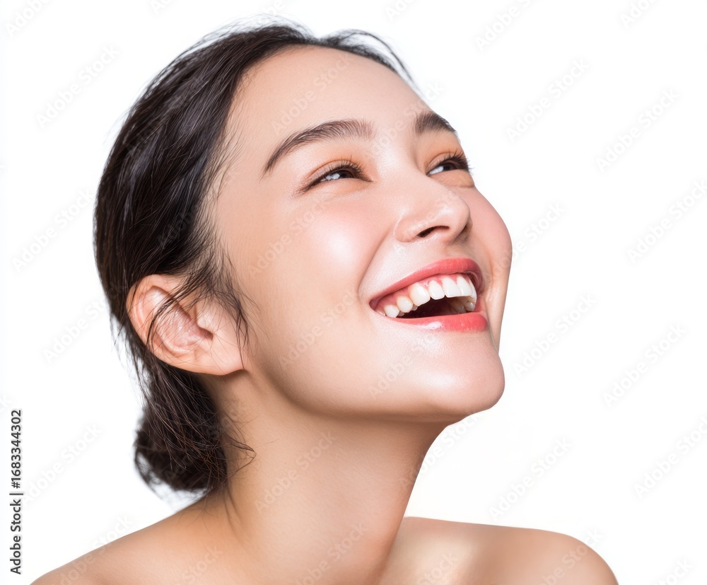 Obraz premium A radiant woman's face, expressing joy and healthy skin, against a plain white background. Her smile is full of vitality, highlighting perfect teeth and a smooth complexion.