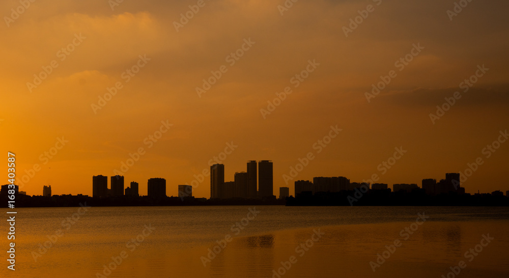 Obraz premium Golden sunset over the lake, silhouetted friends watching the glowing horizon in peaceful harmony.