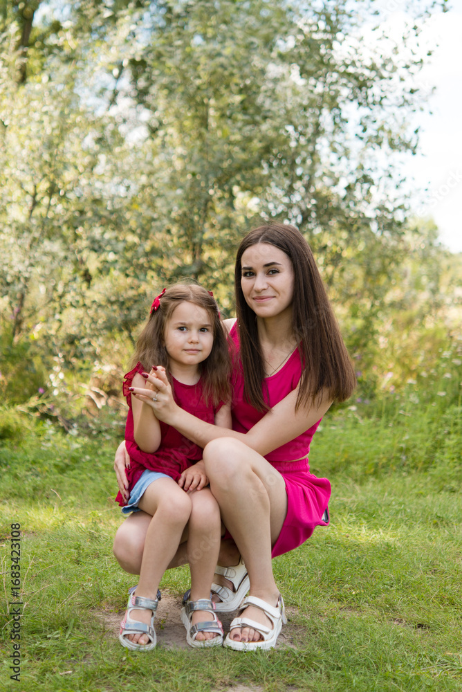 Obraz premium portrait of young mother with a small daughter in summer nature at sunset. Hugs