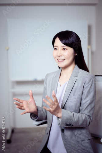 ホワイトボードの前でインタビューに答える女性
