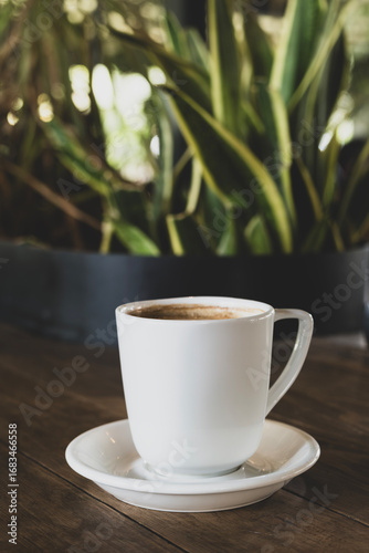 Hot coffee in white mug with dark backdrop. Freshly brewed coffee against black background. Cup of coffee on dark background.