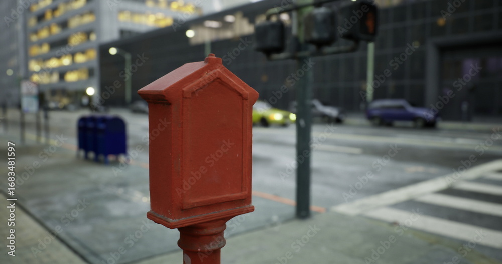 Obraz premium A vibrant red mailbox captures attention on a bustling city street.