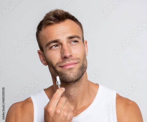 Thoughtful man applies facial serum, showcasing a confident and healthy skincare routine.
