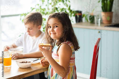 Happy family sister and brother have breakfast with cereal and milk in a kitchen at home