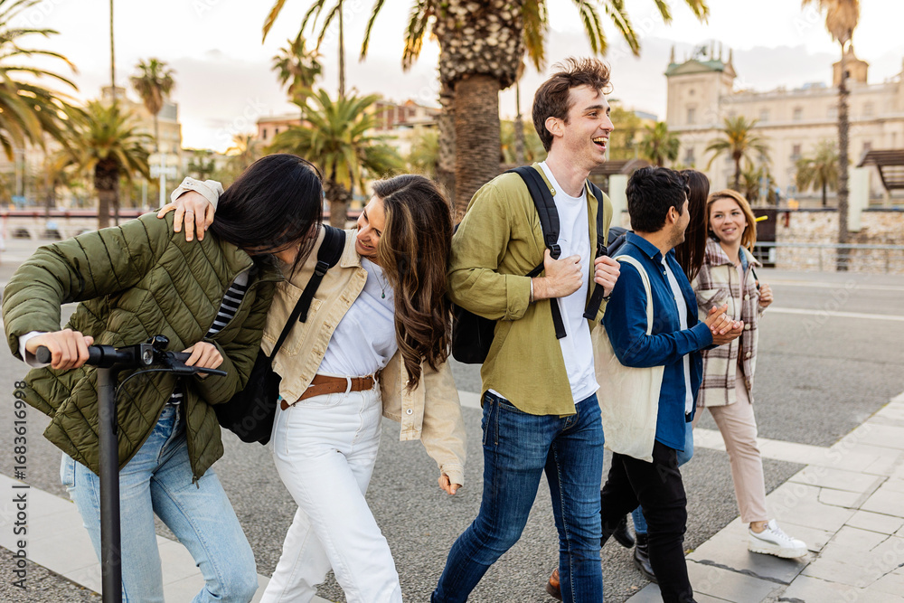 Fototapeta premium Happy millennial generation students walking and talking together at city street