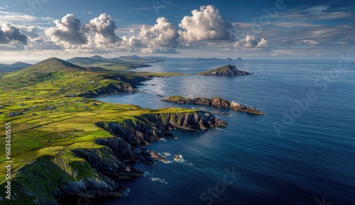 Panoramic coastal view of Ireland's rugged coastline, with rolling hills, green pastures, and dramatic cliffs meeting the azure ocean.  Large, fluffy clouds are scattered across a vibrant blue sky
