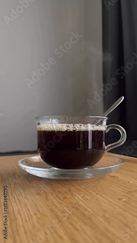 a transparent mug of coffee into which water is slowly poured