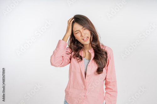A young woman is visibly displaying signs of stress, tightly clutching her head and frowning deeply