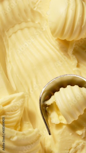 Butter is scraped off with a special butter knife from a pack of butter into a recognizable round shape. Extreme macro close-up, perfect for culinary and advertising projects.