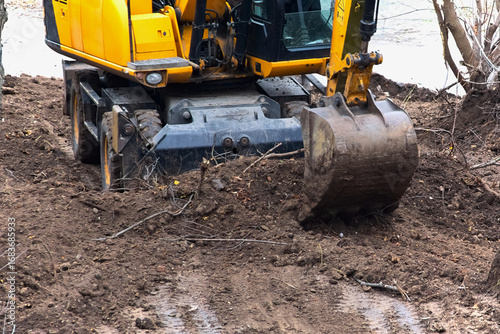 Εκτύπωση καμβά The excavator is digging the soil at a new construction site, operation of heavy construction machinery - the excavator engaged in earth excavation, excavator operation in construction