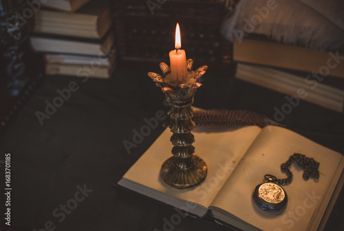 Book and candle on a vintage table, dark academia aesthetic. Evening time