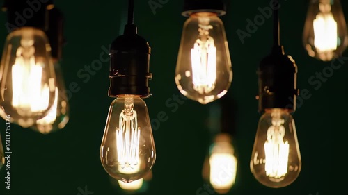 Close Up of Decorative Edison Style Bulbs Suspended Against Dark Green Background in Warm Light