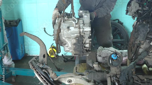 Auto mechanic removes gearbox. Car repair in auto service.