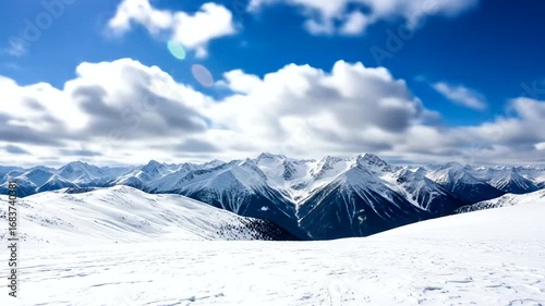 A breathtaking winter landscape showcases snow-capped mountains under a vibrant blue sky filled with fluffy clouds.