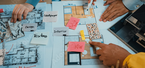 Obraz na plátně Team members engage in an interactive design process, analyzing colorful mood boards and detailed floor plans, showcasing creativity and collaboration in architecture