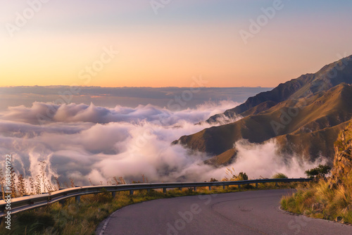 Wonderful panoramic view of a mountain road above the clouds in a natural landscape at sunset.
