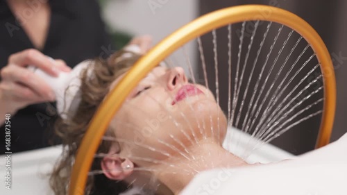 A woman receives hydromassage therapy in a tranquil spa setting, with water gently flowing down her neck, promoting relaxation and rejuvenation through innovative aqua massage techniques.