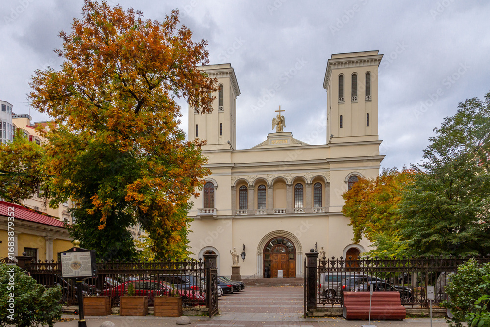 Fototapeta premium Classical Lutheran church facade with ornate cast iron fence and autumn trees in yellow and orange colors. Saint Petersburg, Russia.